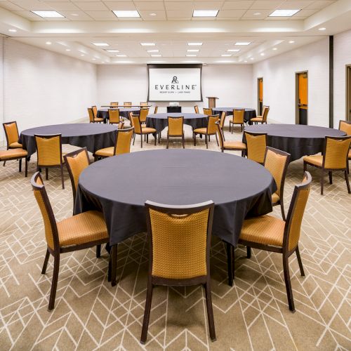 A hotel meeting room with round banquet tables, chairs, and an &ldquo;EVERLINE&rdquo; screen logo on the back wall.
