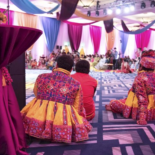 A live cultural performance: dancers in bright embroidered outfits on a lit stage while an audience watches.