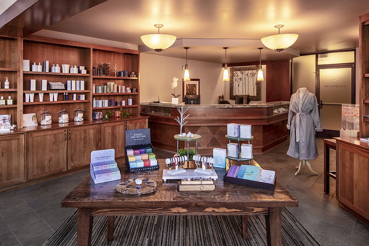 A well-organized spa or boutique store with wooden shelves, various products, a front counter, and a mannequin in a robe on display.