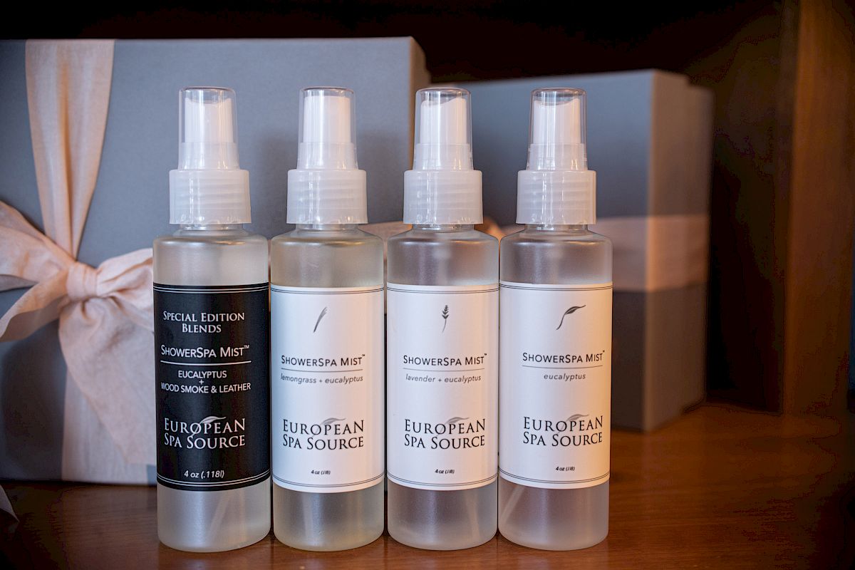 Four bottles of ShowerSpa Mist by European Spa Source are lined up in front of a ribbon-wrapped gift box.