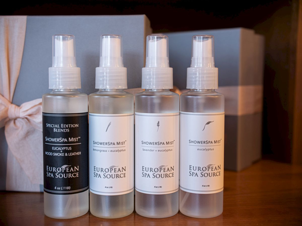 Four bottles of ShowerSpa Mist by European Spa Source are lined up in front of a ribbon-wrapped gift box.