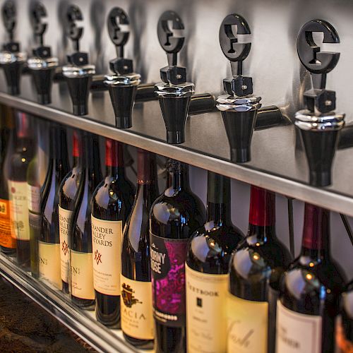 A row of wine bottles placed in a wine dispensing system, designed for serving wine by the glass while maintaining its freshness.