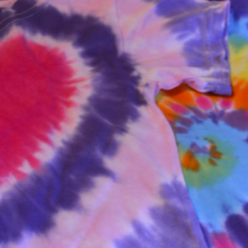 The image shows two colorful tie-dye shirts with vibrant patterns, including a heart-shaped design and a multicolored circular design.