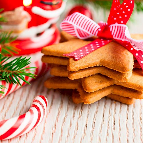 Star-shaped cookies tied with a ribbon are surrounded by candy canes, pine cones, and festive decorations on a wooden surface.