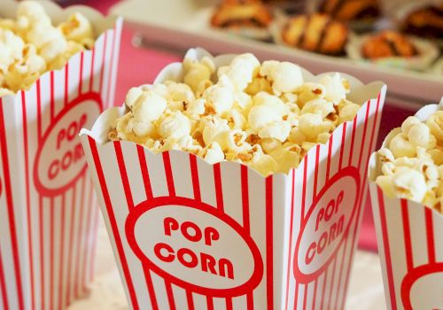 The image shows three containers filled with popcorn in red and white striped boxes labeled 