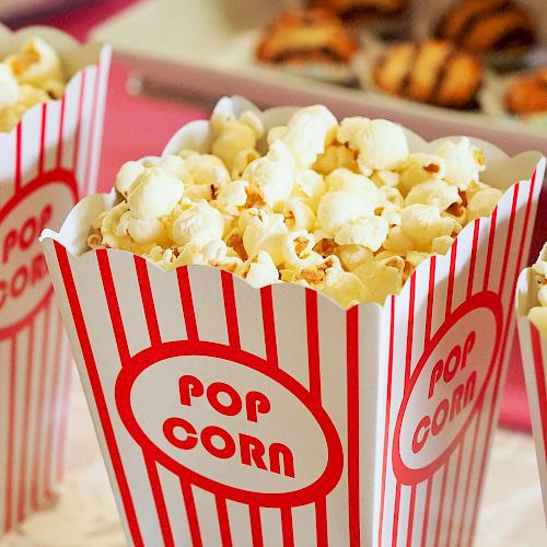 The image shows three containers filled with popcorn in red and white striped boxes labeled 