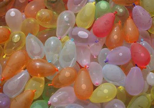 The image shows a large collection of colorful, water-filled balloons in various shapes and sizes.