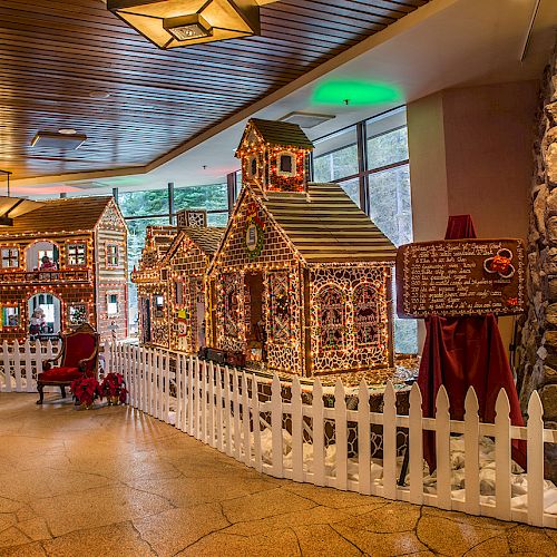 The image shows a festive indoor display featuring gingerbread houses, a white picket fence, a nutcracker statue, and a decorated wreath.