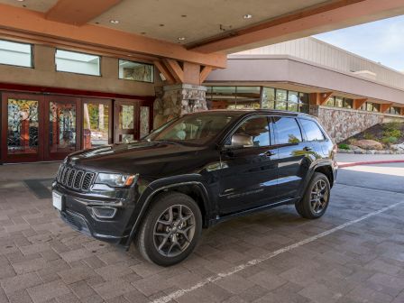 A black Jeep SUV parked in front of a modern building with wooden beams and large windows outside.