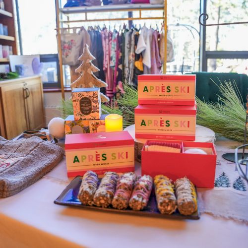 Store display of Apres Ski bath sets, candles and gift boxes on a holiday table near cozy blankets and ornaments.